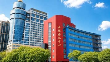 A modern building with a prominent red vertical sign, a blue facade, and a cylindrical glass structure.