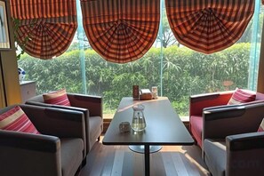 Habitación con sofá, una mesa y vistas a zonas verdes a través de amplias ventanas.