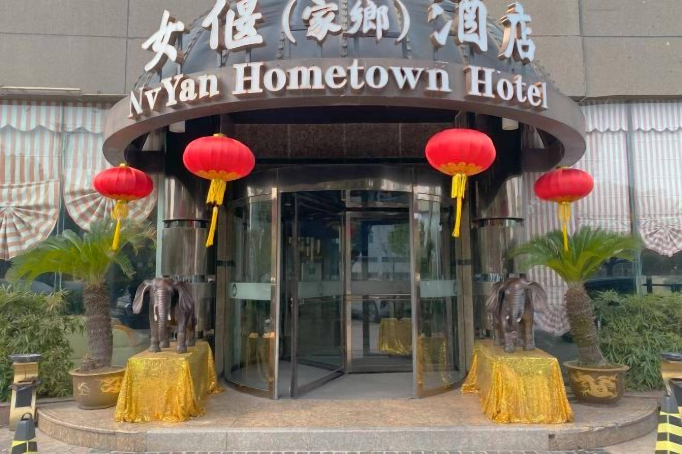 Entrada do Hotel N'Yan Hometown, com porta de vidro e lanternas vermelhas.