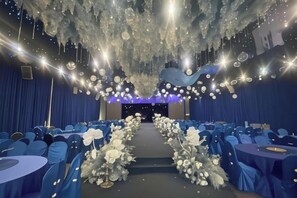 A banquet hall with rows of round tables, a central aisle, and a ceiling adorned with hanging lights and decorations. - ShangHai NvYan Hotel (Shanghai)