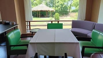 Quarto com mesa e cadeiras, um sofá e vista para um jardim com um coreto.