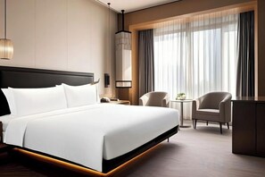 A modern hotel room with a large bed, a desk, two chairs, and a view of the outdoors through large windows. - ShangHai NvYan Hotel (Shanghai)