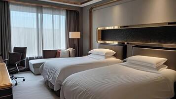 A hotel room with two beds, a desk, and a chair.