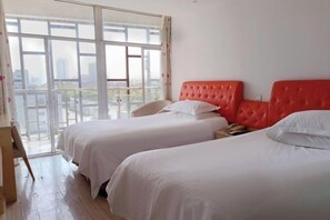 A hotel room with two beds, a wooden desk, and a large window offering a city view. - ShangHai NvYan Hotel (Shanghai)
