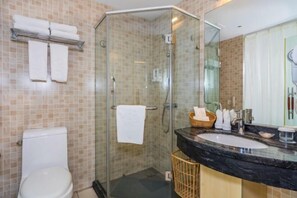 A bathroom with a glass-enclosed shower, a white toilet, a sink with a black countertop, and a mirror. - ShangHai NvYan Hotel (Shanghai)