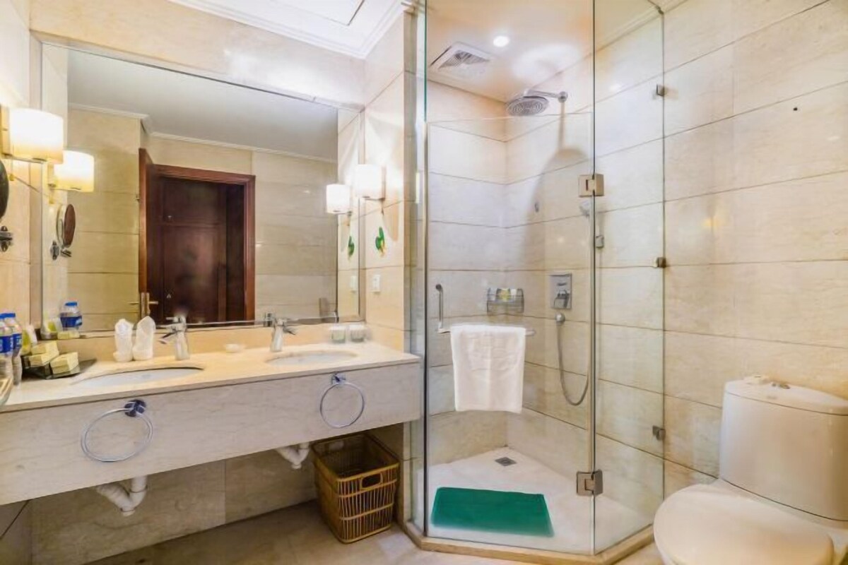 A modern bathroom with a glass-enclosed shower, a large mirror, and a dual sink vanity.
