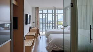 Una habitación de hotel moderna con un ventanal grande, una cama, un escritorio y un televisor.