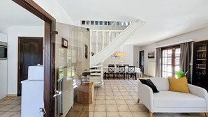 Ein geräumiger Wohnbereich mit Treppe, einem weißen Sofa und einem Esstisch.