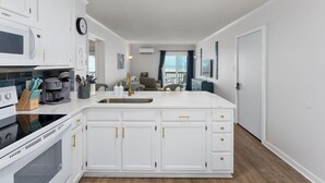 Une cuisine moderne avec des meubles blancs, un grand îlot central, un four à micro-ondes et une machine à café.