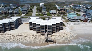 Un quartier résidentiel situé sur la côte, avec de nombreux immeubles à plusieurs étages, une plage de sable et une jetée qui s’avance dans l’eau.