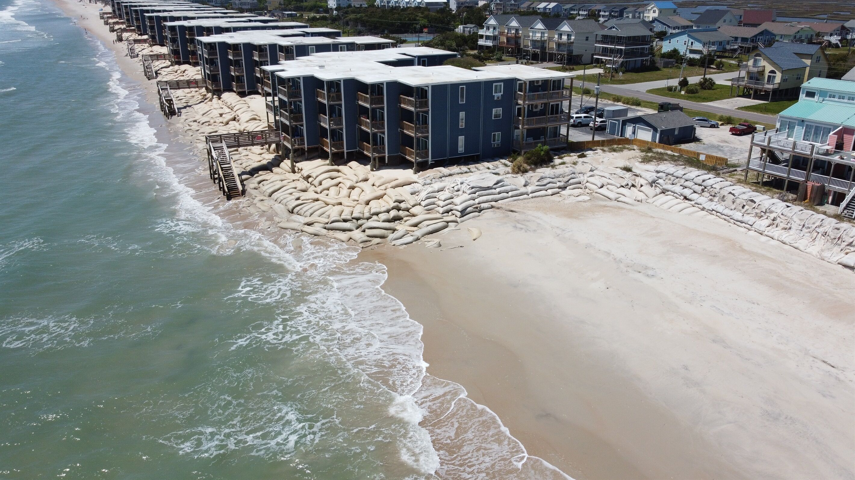 Ein Hotel direkt am Strand mit mehreren Gebäuden, einem Sandstrand und Wellen.