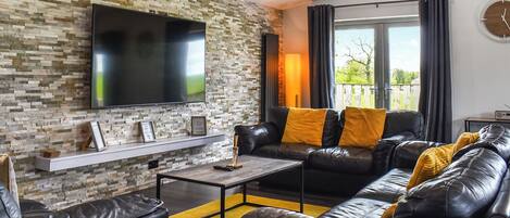 Una sala de estar moderna con una pared de piedra, un sofá de cuero y un televisor de pantalla plana.
