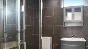 A bathroom with a glass-enclosed shower, a toilet, and a sink.
