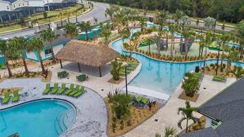 A resort with a central swimming pool, lounge areas, and a thatched-roof structure.