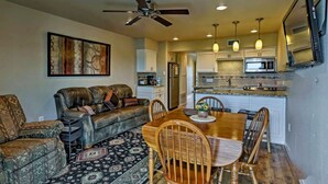 A living room with a sofa, a dining table with chairs, a ceiling fan, and a kitchen area with cabinets and a microwave. - Updated Comal River Condo, 2 bedroom,2 bath, 1 mi to Schlitterbahn (New Braunfels)