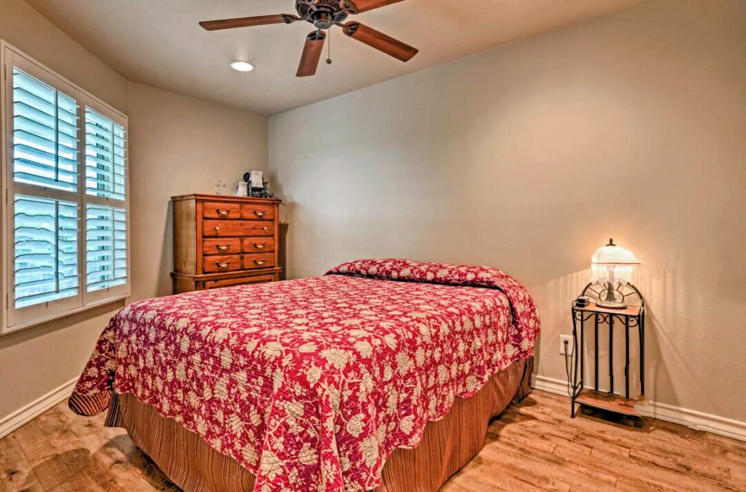 Une chambre à coucher avec un lit, une commode, un ventilateur de plafond et une table de chevet avec une lampe.