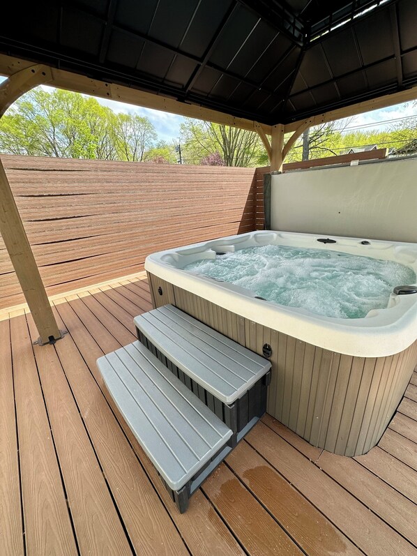 A hot tub with steps leading up to it, surrounded by a wooden deck and a covered area. - Experience the Ultimate Getaway at Our Stunning Riverfront Property!!! (St. Joseph)