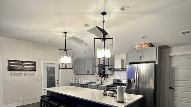 A modern kitchen with a central island, bar stools, and stainless steel appliances. - Experience the Ultimate Getaway at Our Stunning Riverfront Property!!! (St. Joseph)