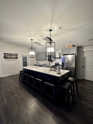 A modern kitchen with a central island, bar stools, and stainless steel appliances. - Experience the Ultimate Getaway at Our Stunning Riverfront Property!!! (St. Joseph)