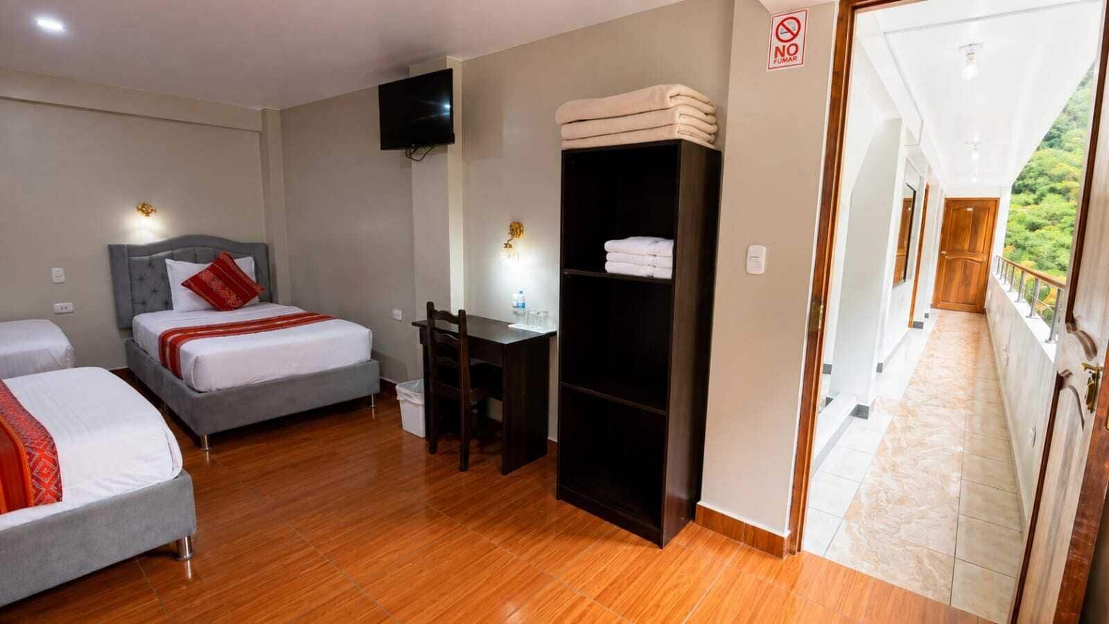 A hotel room with two beds, a desk, a television, and a wardrobe.
