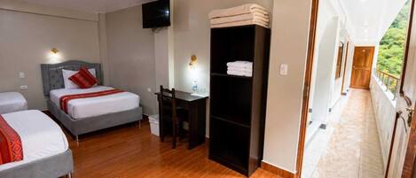 Une chambre d’hôtel avec deux lits, un bureau, une télévision et une armoire.