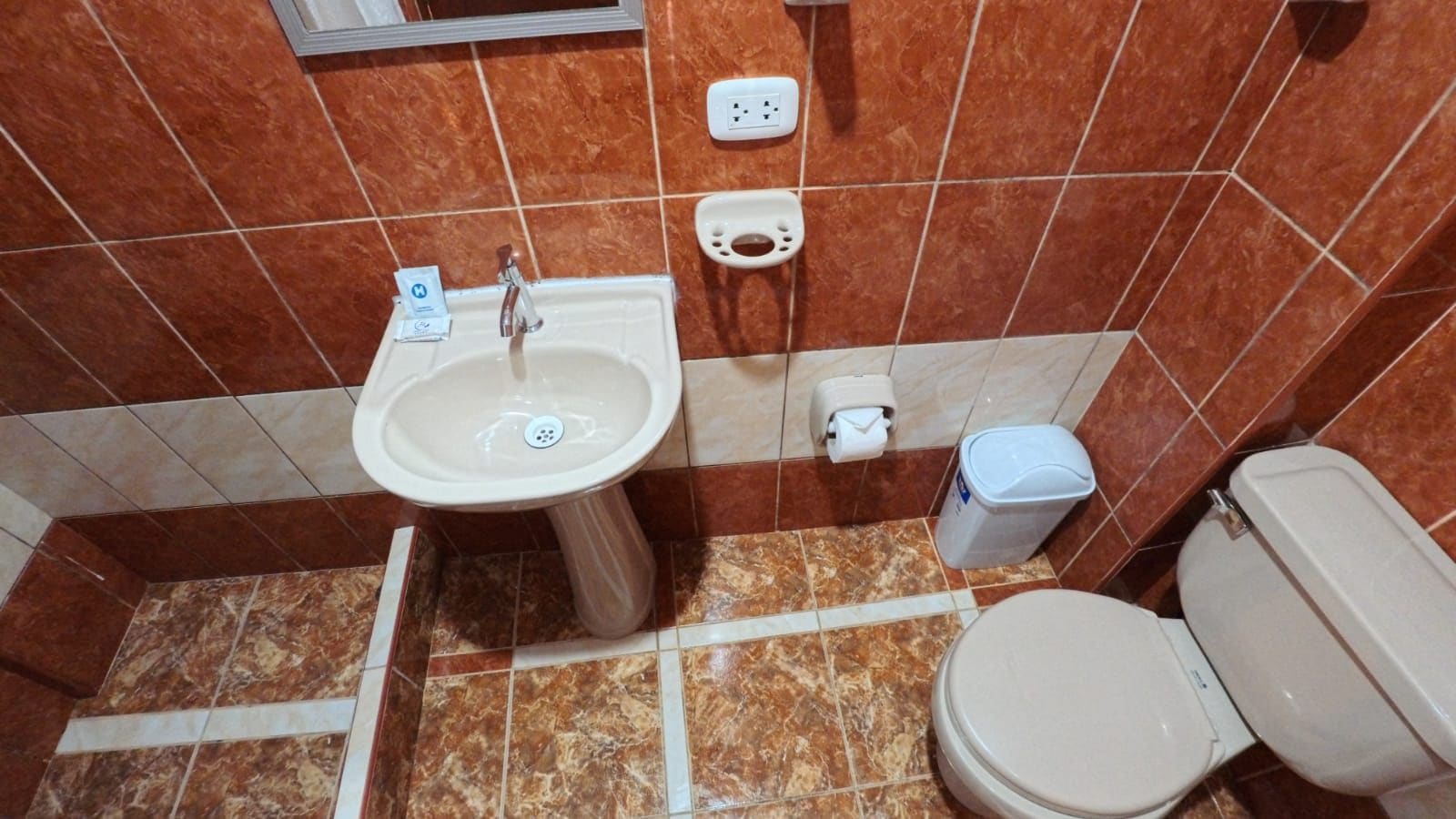 Casa de banho com lavatório, sanita e um contentor de lixo.