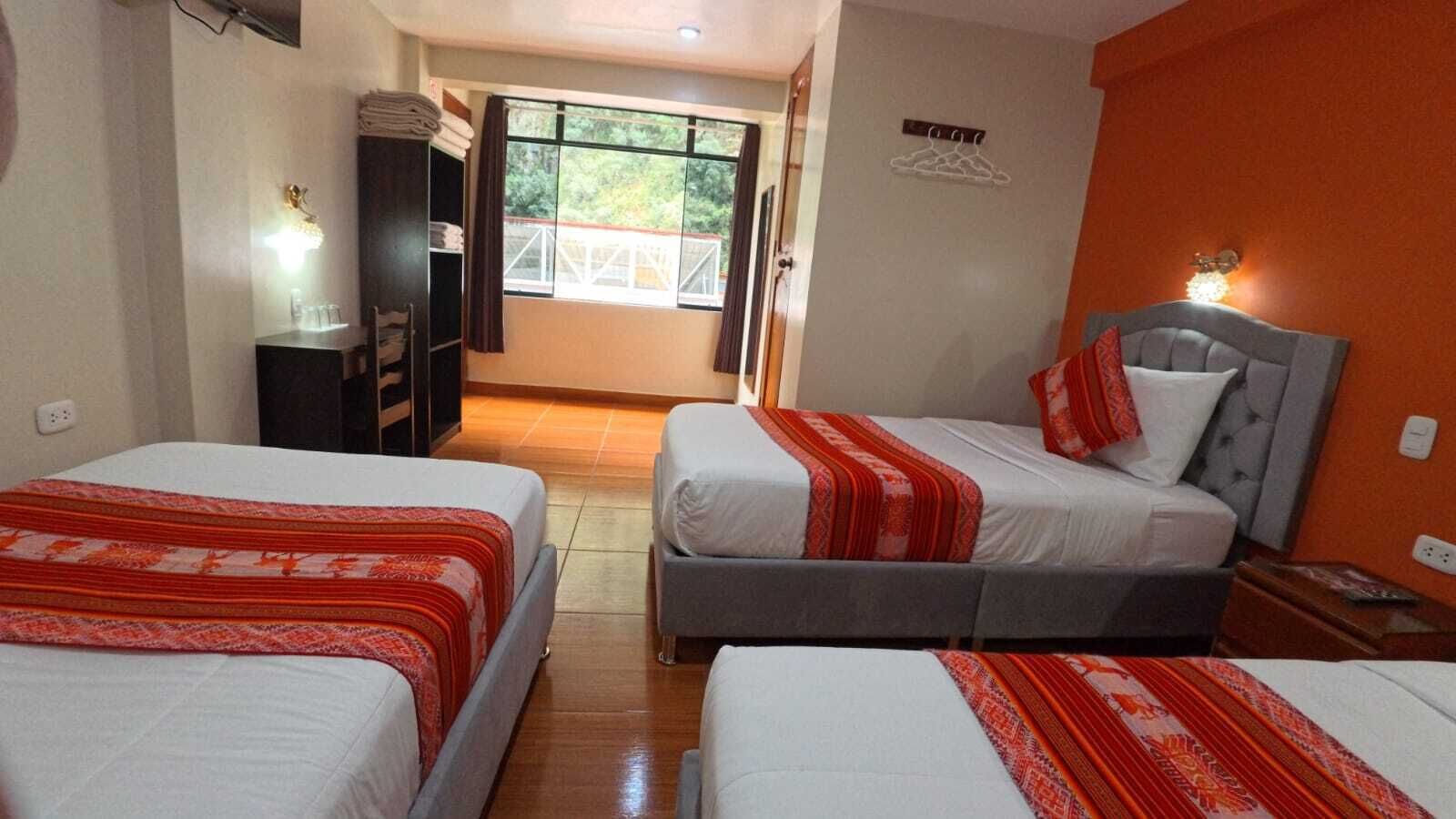 Habitación de hotel con dos camas, un armario, un espejo, una ventana con vistas y un aplique de pared.
