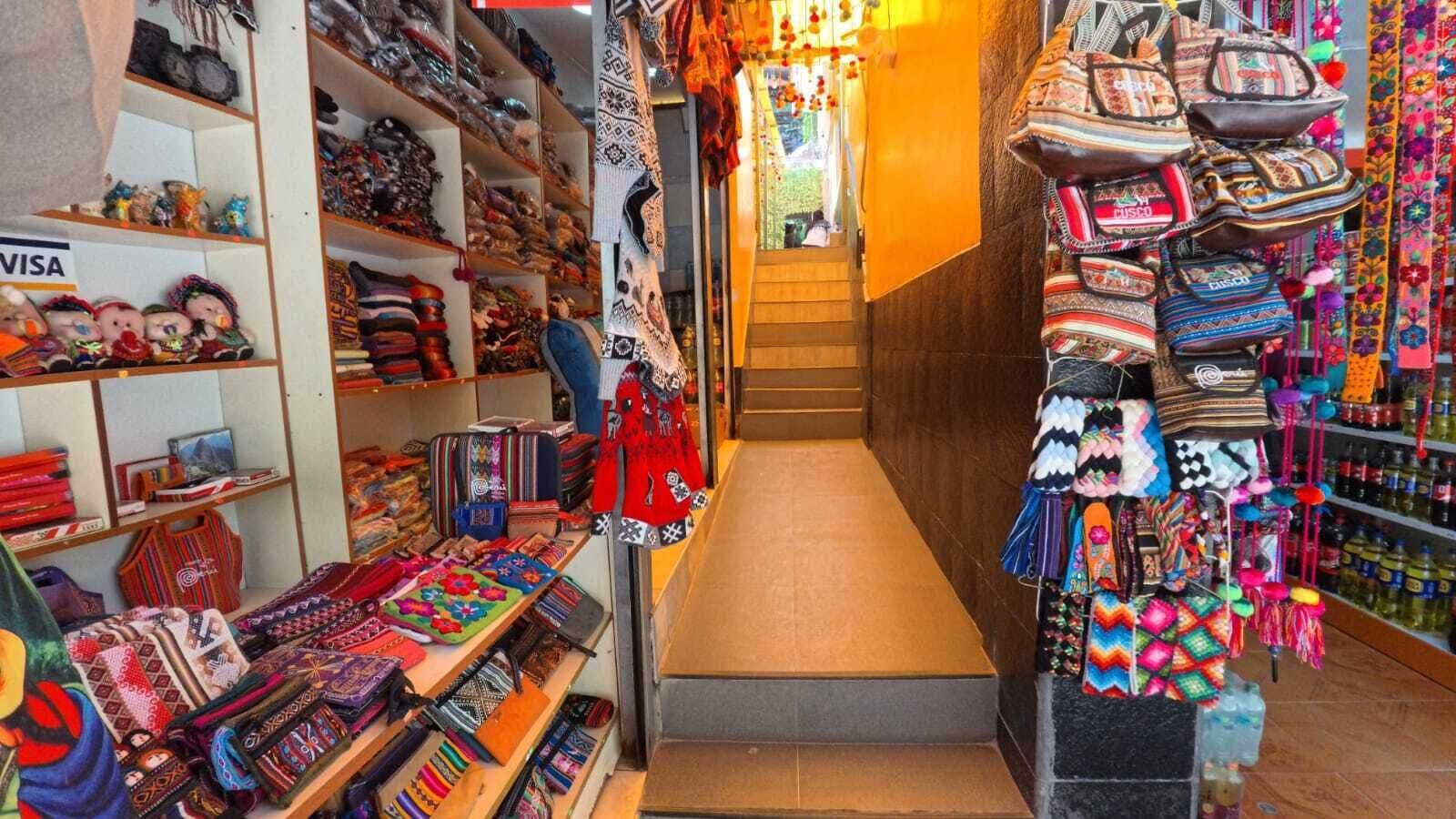 Un corridoio stretto fiancheggiato da scaffali pieni di borse e accessori.