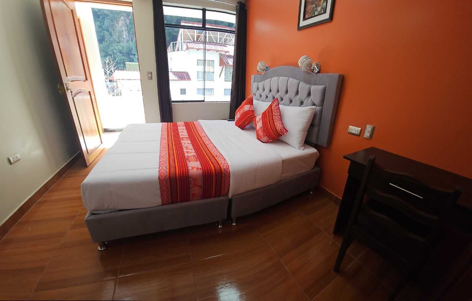 A bedroom with a bed, a window, and a view of buildings outside.