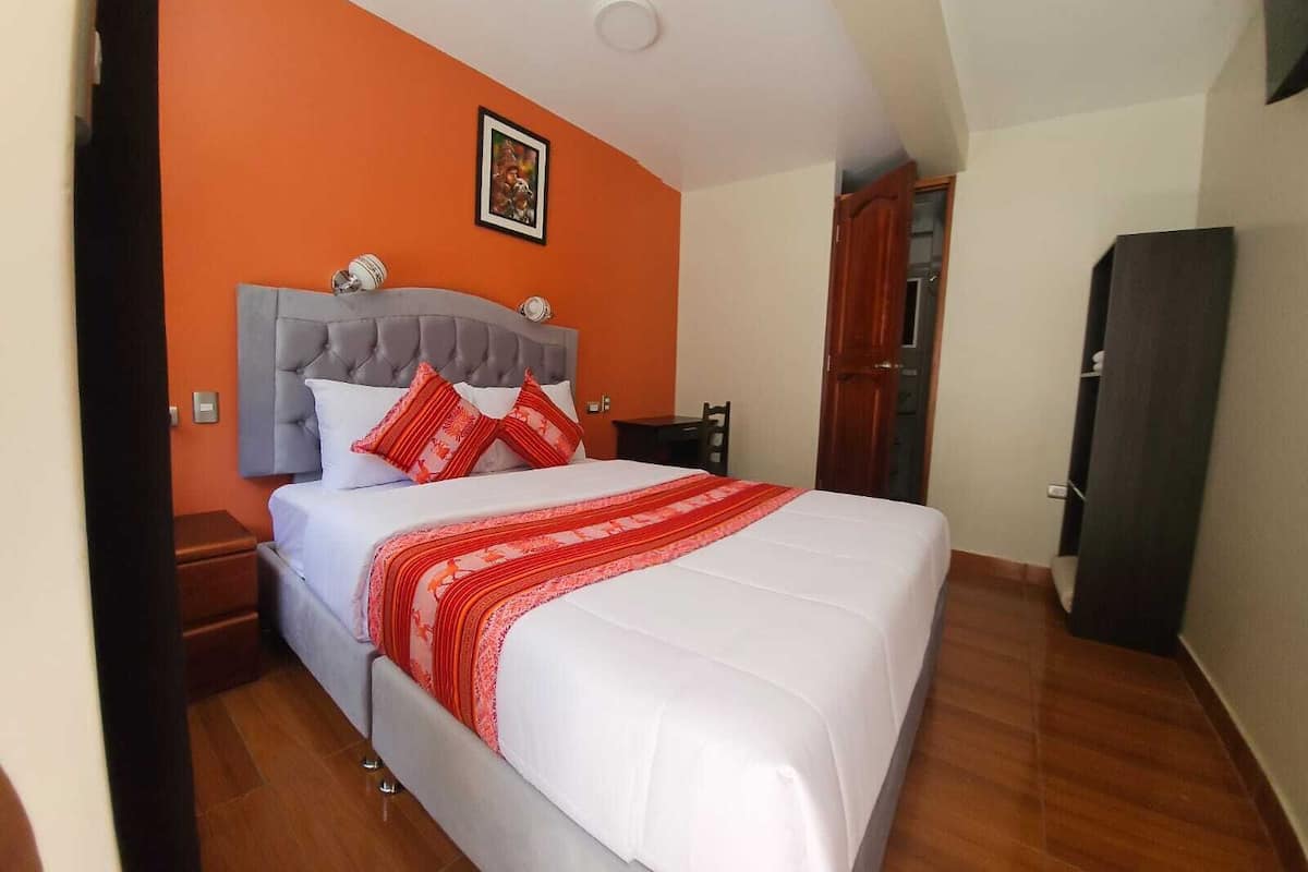 Une chambre à coucher avec un lit, une table de chevet, une armoire en bois et un mur orange.