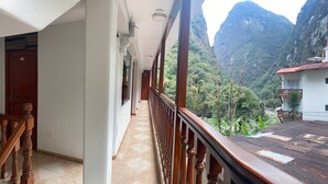 A corridor with a wooden railing, a tiled floor, and a view of a mountainous landscape. - Hotel Horizonte (Machu Picchu)