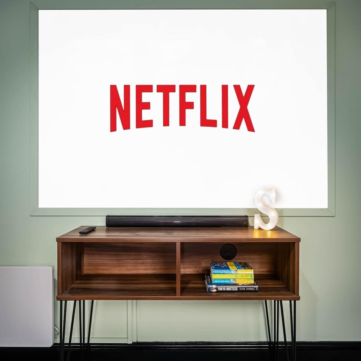 Un téléviseur fixé au mur, avec le mot « NETFLIX » affiché à l’écran.