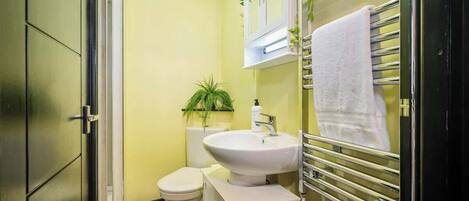 A compact bathroom with a white sink, toilet, and a towel rack.