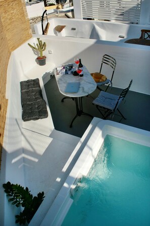 Ein Poolbereich auf dem Dach mit Tisch und Stühlen, einem Blumentopf und einer kleinen Sitzecke.