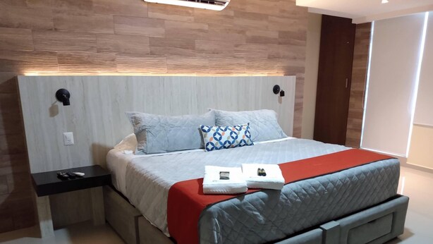 A modern bedroom with a bed, nightstands, and a red blanket. - EXECUTIROOMS Veracruz (Veracruz)