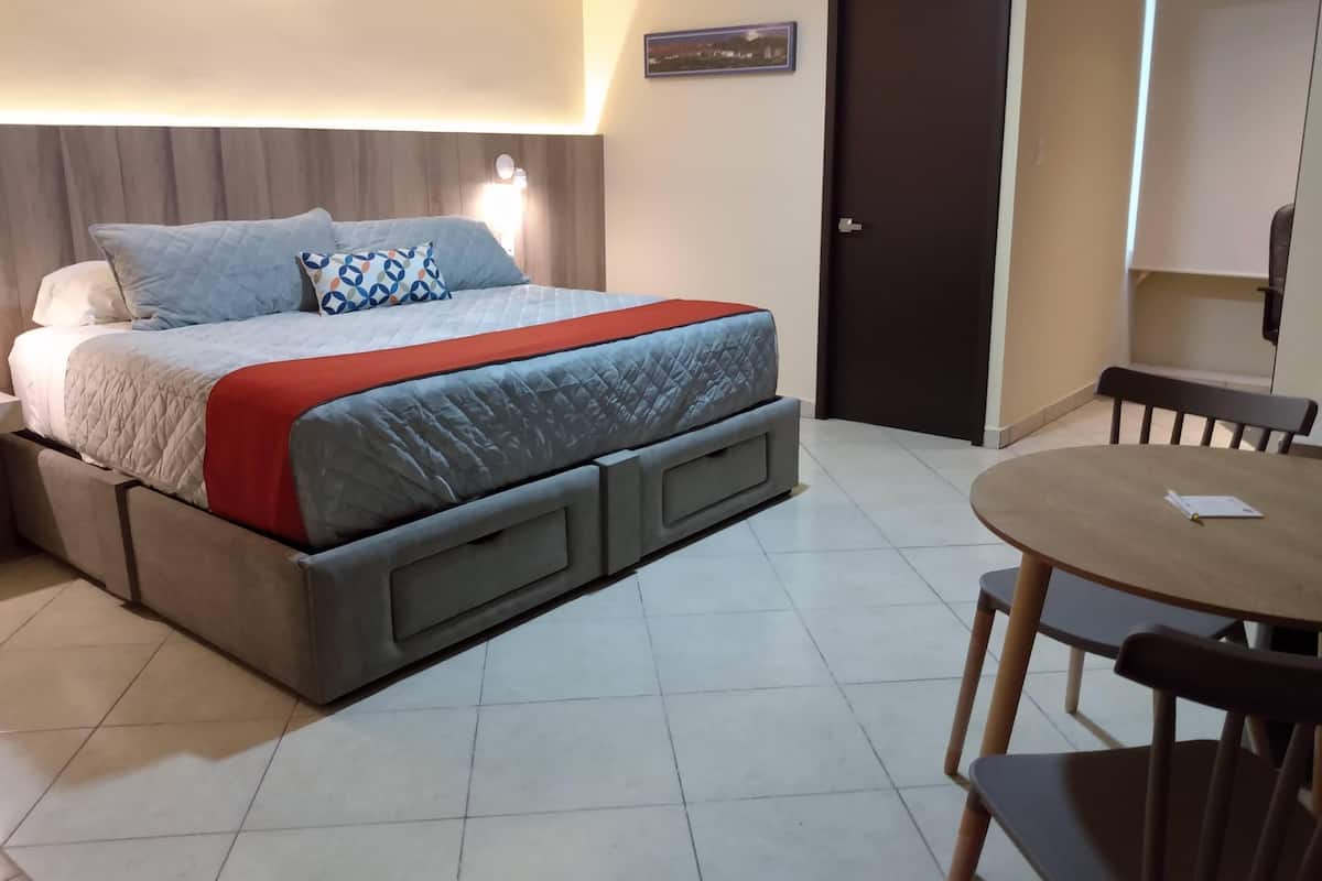 A neatly arranged bedroom with a bed, bedside tables, a chair, and a small table.