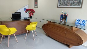 A reception area with a glass desk, two yellow chairs, a wooden cabinet, and a framed picture on the wall. - EXECUTIROOMS Veracruz (Veracruz)