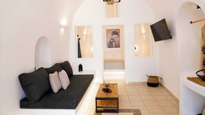 Ett modernt vardagsrum med en svart soffa, ett träbord och en tv som är monterad på väggen.