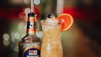 Une bouteille de rhum britannique de la marque Pusser's, ainsi qu'un cocktail agrémenté d'une tranche de pamplemousse et d'une paille.