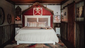 A bedroom with a large bed, wooden walls, and a barn-style headboard. - MyFarm Stay/Rustic Barn Charm with Modern Comforts/walk to dining. Pet-Friendly! (Merlin)