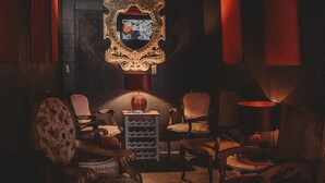 A dimly lit room with a large ornate mirror, several upholstered chairs, and a small table with a vase. - MyFarm Stay/Rustic Barn Charm with Modern Comforts/walk to dining. Pet-Friendly! (Merlin)