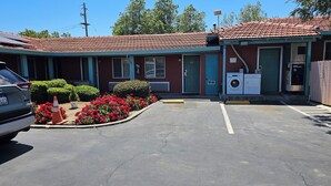 Ein Motel mit rotem Ziegeldach, einem Parkplatz und einem kleinen Garten mit roten Blumen.
