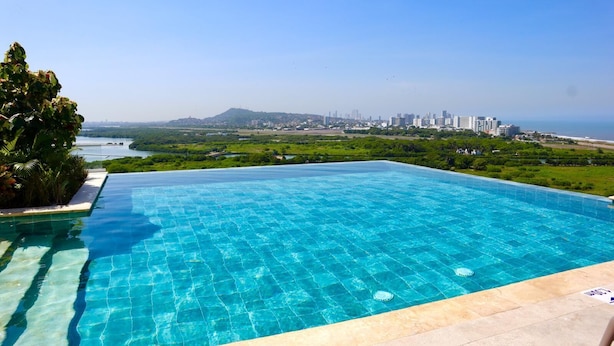 A rectangular infinity pool with clear blue water, surrounded by a tiled deck. - 5 minutes walk to the beach - Unit with Jacuzzi on private balcony (La Boquilla)