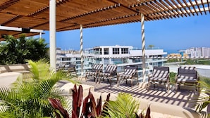 A rooftop lounge with sun loungers and a wooden pergola, overlooking a cityscape and the sea. - 5 minutes walk to the beach - Unit with Jacuzzi on private balcony (La Boquilla)
