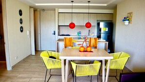 A modern kitchen with wooden cabinets, a black refrigerator, and a dining area with a wooden table and yellow chairs. - 5 minutes walk to the beach - Unit with Jacuzzi on private balcony (La Boquilla)