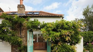 Une maison avec une cheminée en briques, un toit en tuiles et une porte d’entrée dotée d’un cadre vert.