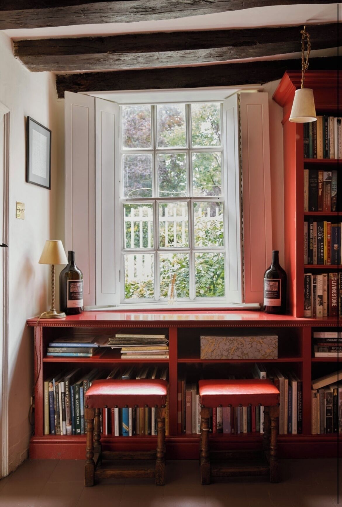 A cozy reading nook with a large window, bookshelves, and two wooden benches.
