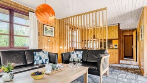 A cozy living room with a wooden partition, a sofa set, a coffee table with decorative items, and a view of the outdoors. - 2 bedroom beautiful home in Toftlund (Toftlund)