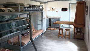 Una habitación pequeña con literas, kitchenette y un rincón de comedor.