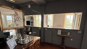 A room with a wooden dresser, a mirror, and a window with a view of greenery. - Duomo Attic Luxury Experience (Milano)